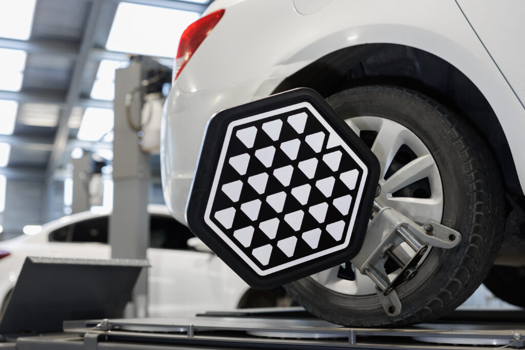 Vehicle inside garage workshop for auto camber toe check fixing work. Car wheel balancer calibrate with laser reflector attach on each tire to center driving adjust